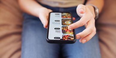 Person browsing food options on a smartphone while sitting down.