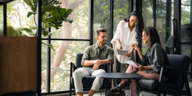 Três pessoas em reunião informal em escritório moderno.