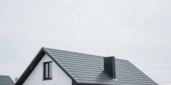 House roof with dark grey tiles and chimney.