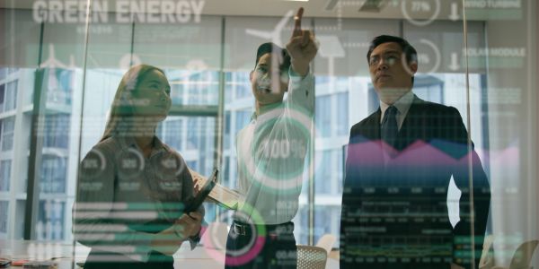 Business team discussing green energy statistics on a transparent screen.