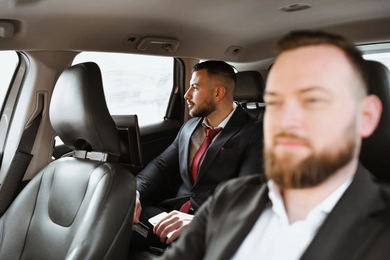 Confident Businessman Enjoying Car Ride With His Personal Driver