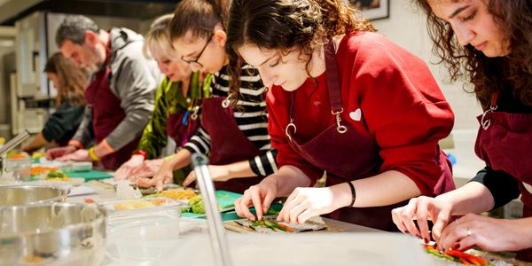 Group of people focused on preparing food together in a kitchen.