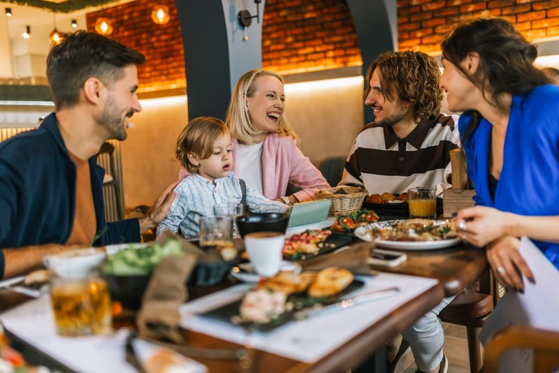 Family and friends gathered in a restaurant to eat delicious food, talk, drink and hang out.