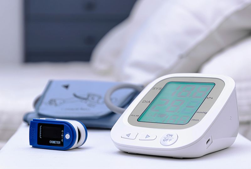 Electronic blood pressure monitor and pulse oximeter in foreground and blurred background.