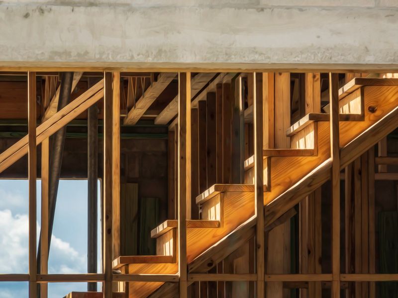 Sunlit wooden stairway inside a single-family house under construction, with concrete lintel at top and bright sky beyond window opening. Light digital-oil painting effect.