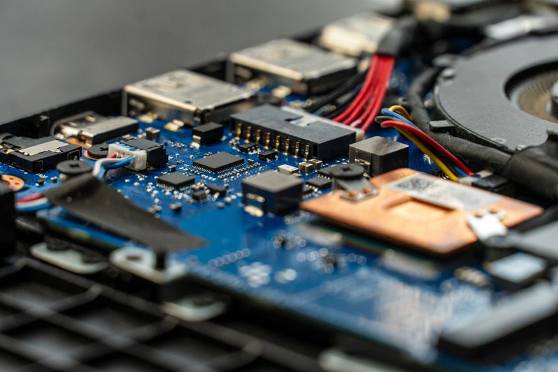 Detailed view of a circuit board inside a laptop reveals various components, wiring, and thermal management elements, illustrating technology and precision engineering
