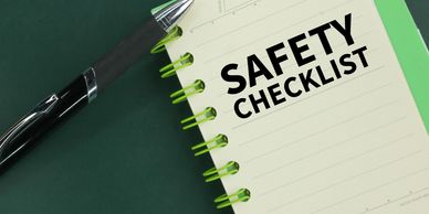 Pen and notebook with a safety checklist on a dark green surface.
