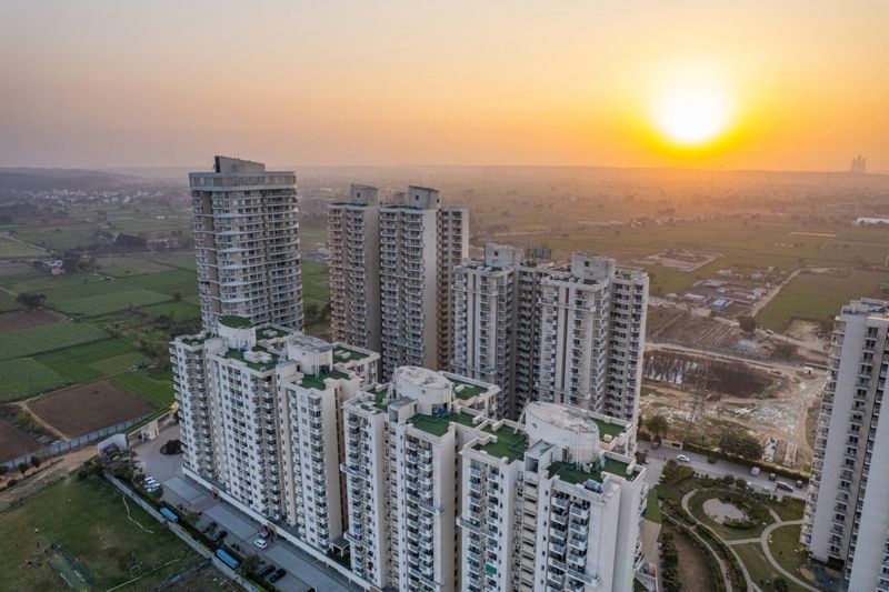 aerial drone shot of luxury rich opulent high rise buildings for residence office shopping surrounded by green fields with mountains off in the distance showing living in the middle of nature