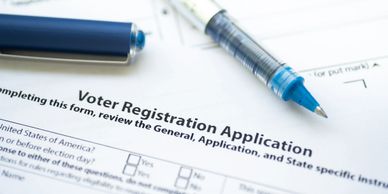A voter registration form with pens ready for filling out.