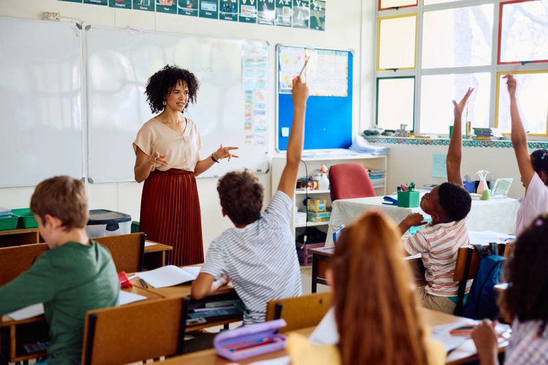 School children sitting at desks keen to answer the teacher's question