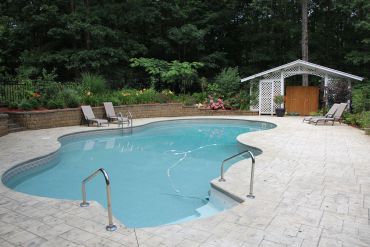 A backyard swimming pool with lounge chairs and a small shed.