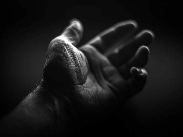 Close-up of an open hand in dramatic black and white lighting.