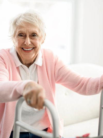 Smiling senior woman using walker – CAP/DA program for disabled adults
