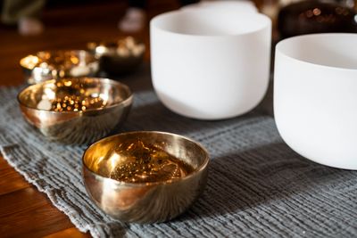 Golden and white singing bowls arranged on a textured cloth.