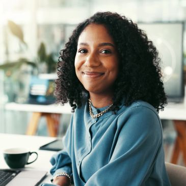 Jeune femme souriante aux cheveux bouclés dans un bureau.