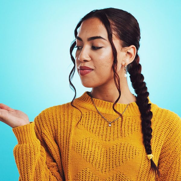 Woman in mustard sweater looking at her open hand.