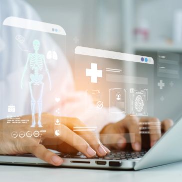 Person using a laptop with holographic medical displays.