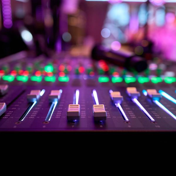 Audio mixing console with glowing sliders and buttons.