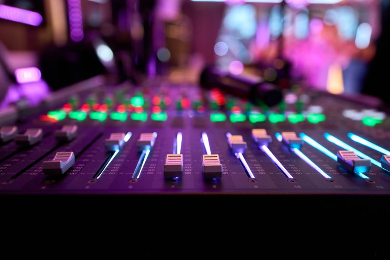 Mixing console with illuminated faders and knobs, creating a vibrant atmosphere in a music production environment