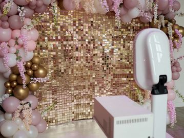 A photobooth setup with pink and gold decorations.
