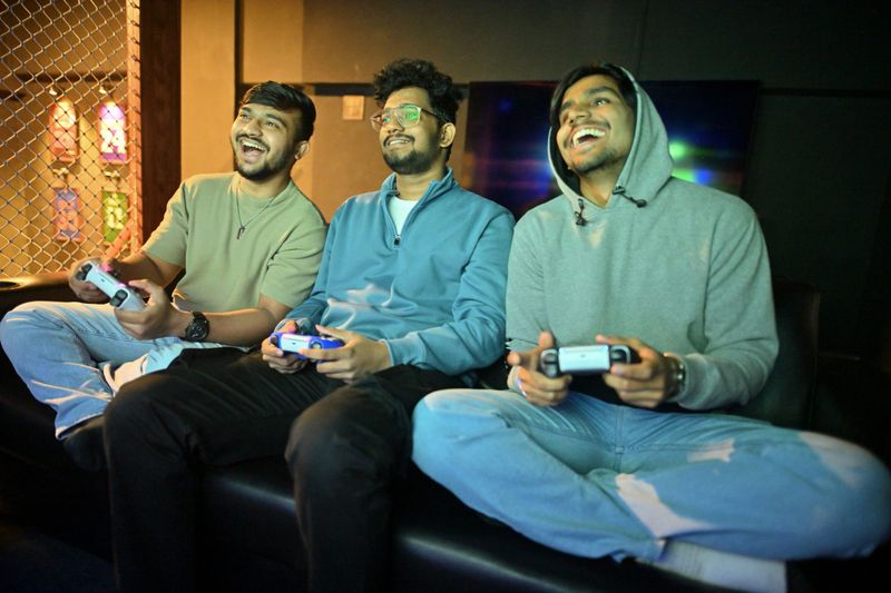 A captivating shot of three males deeply focused on playing a video game. Their expressions show determination and engagement as they hold controllers, fully immersed in the gameplay.