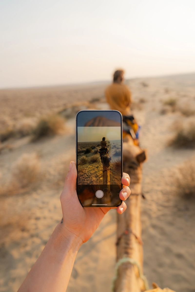 POV photographing with smartphone riding on camel through the desert near Jaisalmer at sunset