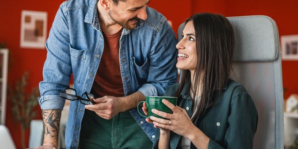 A man and woman share a warm moment with coffee and smiles indoors.