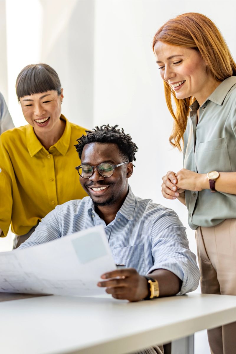 A diverse group of colleagues happily collaborate on a project in a bright, modern office setting. The team is engaged and focused, sharing ideas and ensuring a successful outcome.
