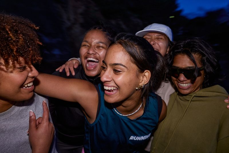 Group of gen z female runners laughing together after a run