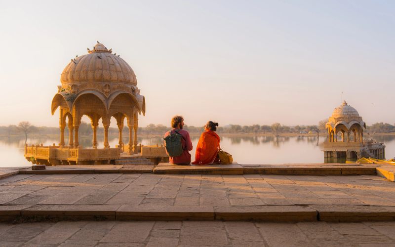 Man and woman  enjoying scenic sunset at Gadisar Lake in Jaisalmer, India
