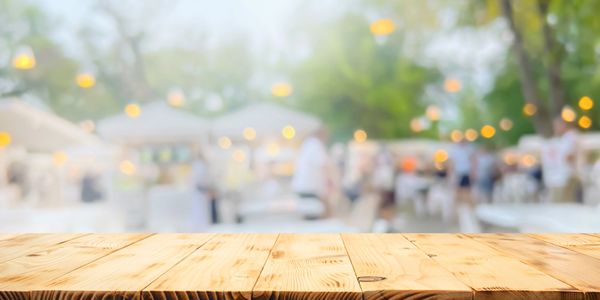 Empty wooden table with blurred outdoor party background.