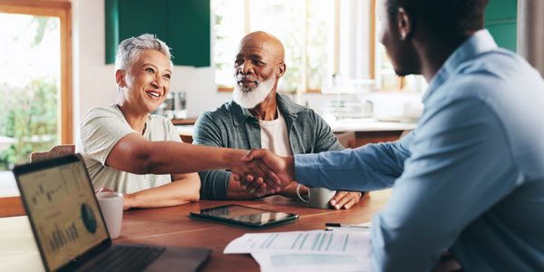 Couple shaking hands with advisor during meeting.