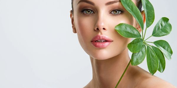 Beautiful woman with clear skin holding green leaf.