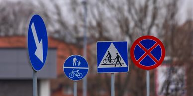 A group of various traffic signs along a road with a blurred background.