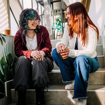 Two friends sitting on stairs chatting happily.