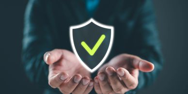 Businessman holding a digital shield with a green check mark symbolizing security.