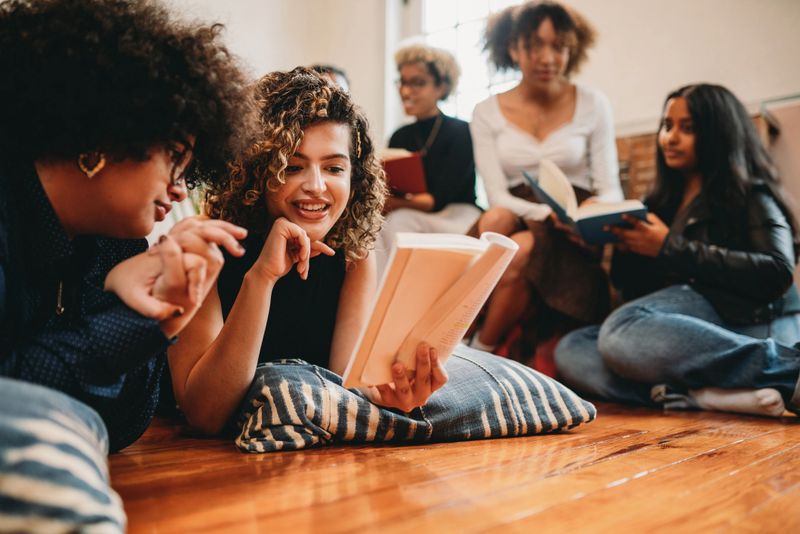 Young friends are reading books together in their book club. They are having fun together.