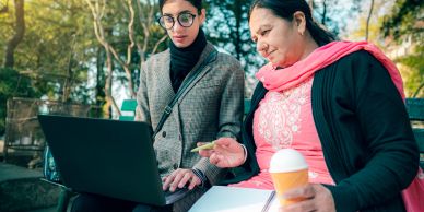 Two people looking at a laptop outdoors.