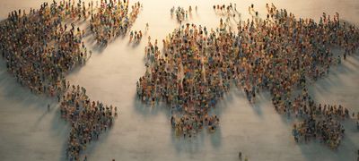 A large crowd forms a world map on the ground.