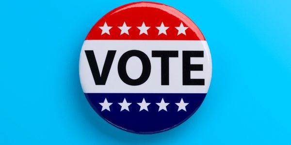 A patriotic vote button with stars on red, white, and blue background.