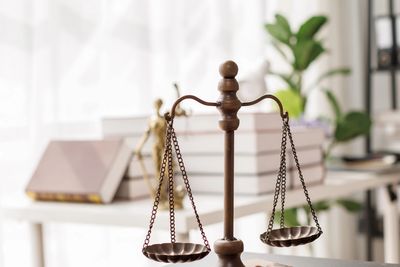 Wooden justice scales and gavel on a desk in a law office.