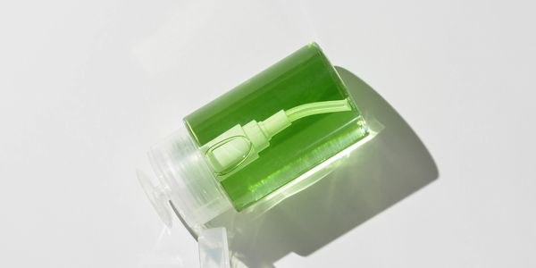 A green liquid-filled pump bottle lying on its side with an open cap.
