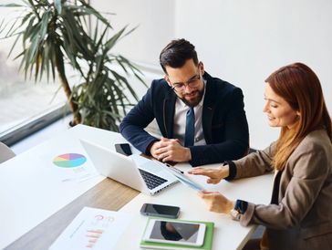 Two colleagues discussing data charts in a modern office.