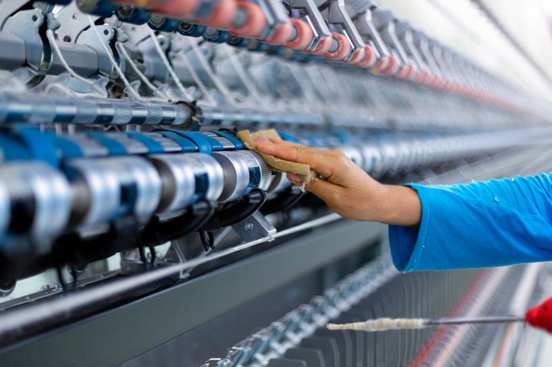 Worker maintaining machinery in a textile factory. Engineer worker work design program machine in textile factory. industry.