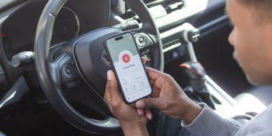 Person using a security app on their phone inside a car.