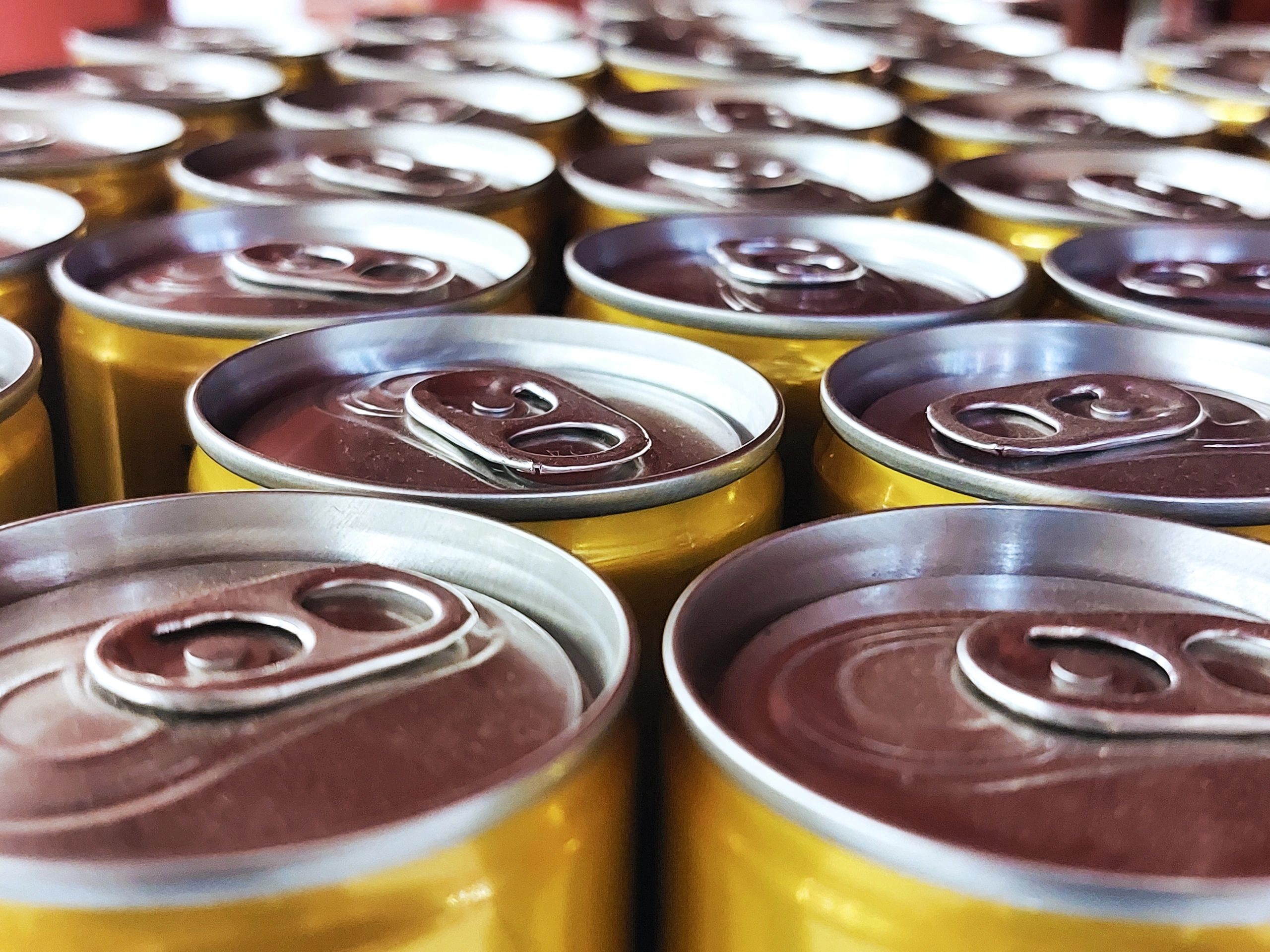 Close-up of unopened yellow aluminum cans arranged in rows.
