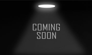 Text 'COMING SOON' illuminated by a spotlight on a dark background.