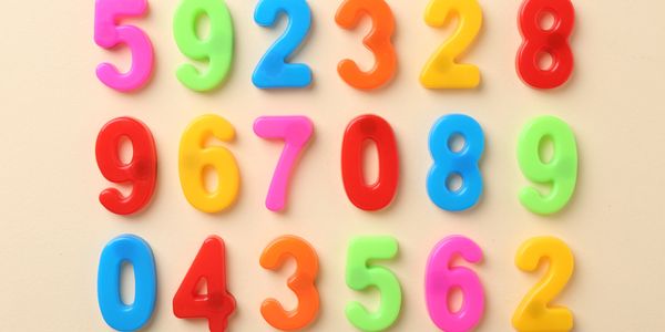 Colorful plastic numbers arranged in a grid on a beige background.