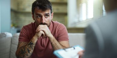 A man anxiously listens during a therapy session.