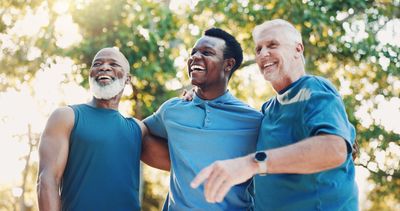 Three men smiling and posing outdoors.
